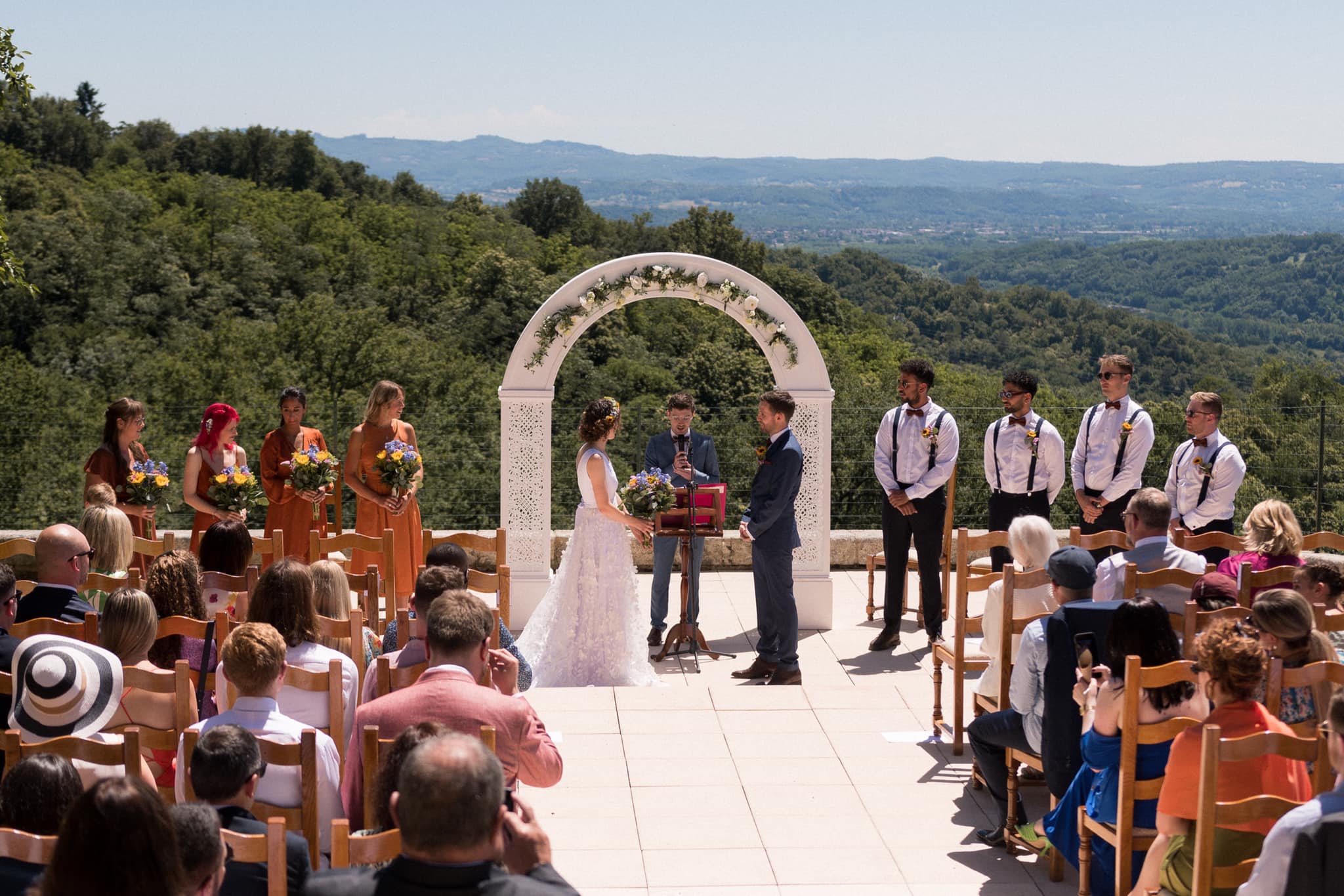 Wedding ceremony with guests, bridesmaids in terracotta, hills rolling away in the distance
